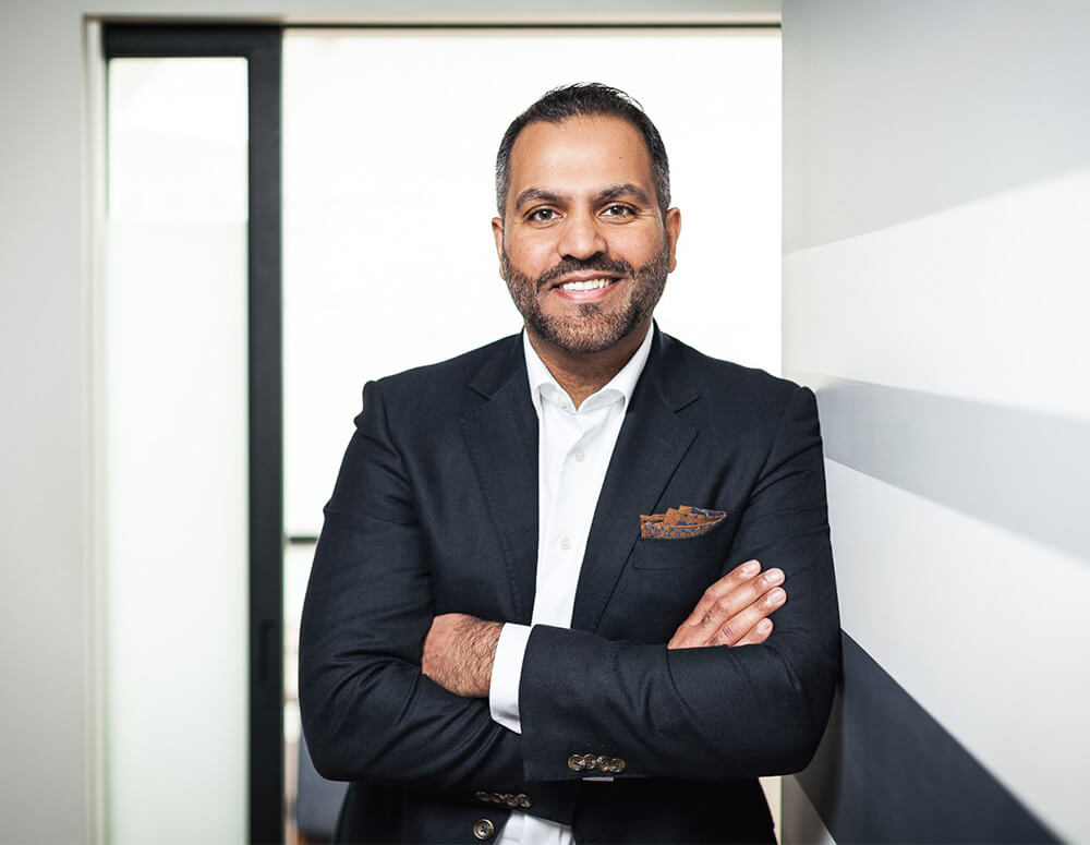 A confident man with crossed arms standing in an office.